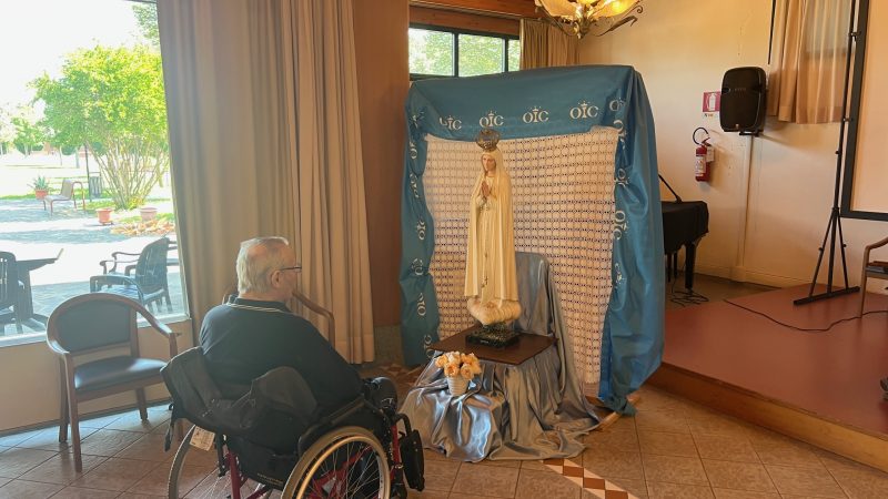 Un'ospitre della residenza in preghiera davanti la statua della Madonna.