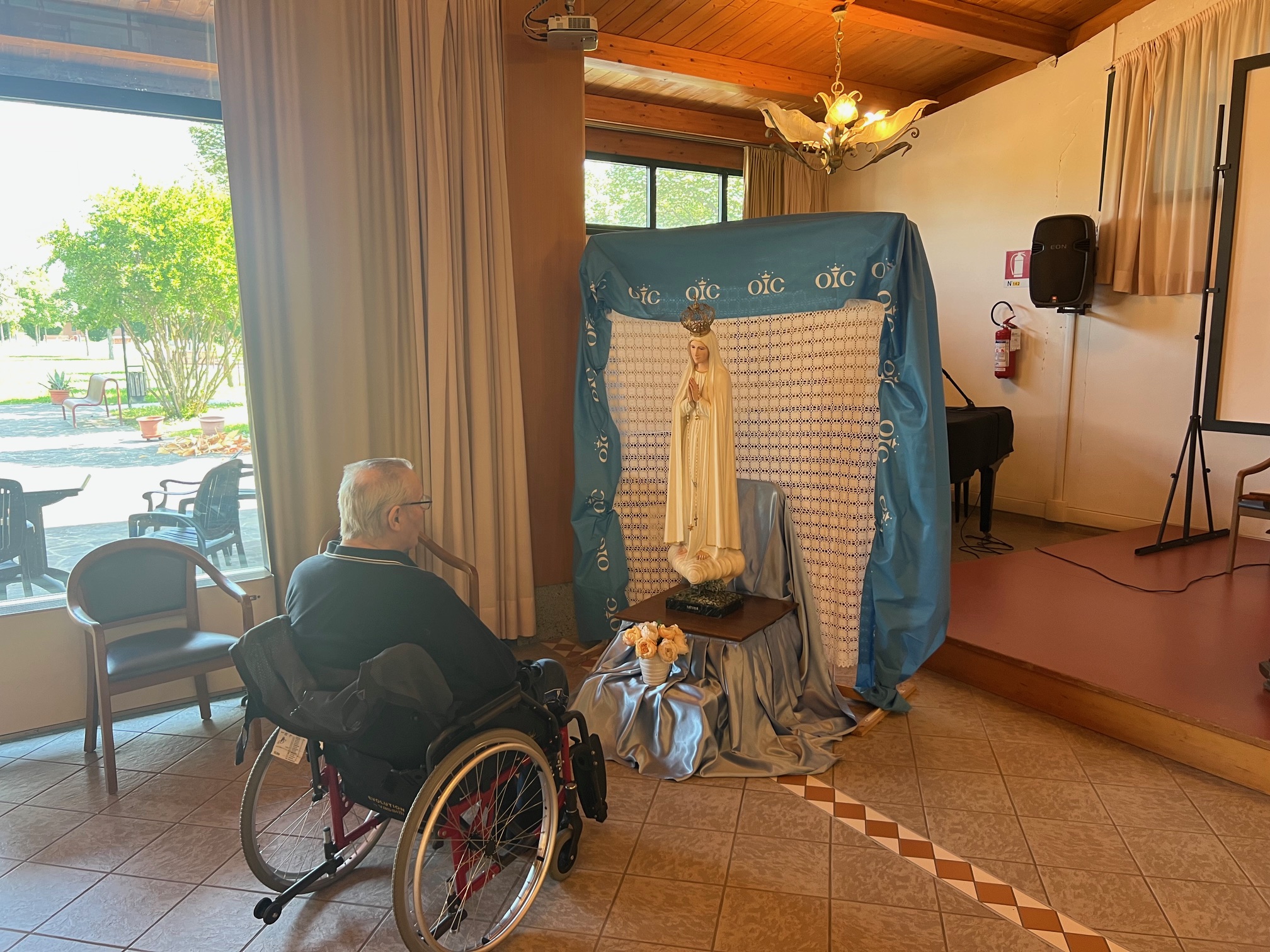 Un'ospitre della residenza in preghiera davanti la statua della Madonna.